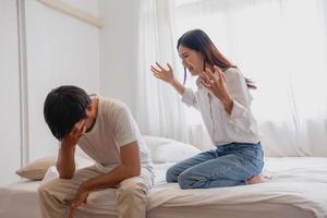 Internal violence. family conflict A woman is violently reprimanding her husband in an angry mood. make the husband feel bad In the bed inside the house, family quarrel concept. photo