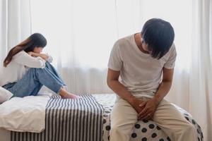 The husband is unhappy and disappointed in the erectile dysfunction during sex while his wife sleeping on the bed. Sexual Problems in Men, The concept of erectile dysfunction according. photo