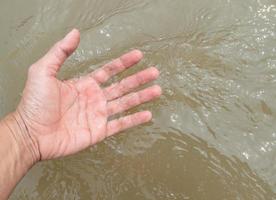 el mano de un joven hombre es conmovedor el fluido agua. foto