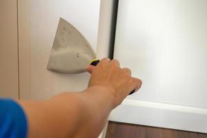 Man repairing crack white wall with spatula photo