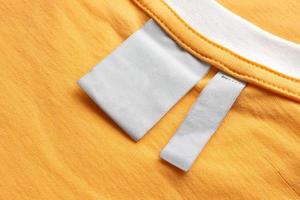 Blank white laundry care clothes label on yellow fabric texture background photo