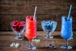 Summer Sicilian granite dessert, frozen raspberries, blueberry juice in large glass glasses on a wooden background with fresh berries. Summer cool, tonic crushed ice cocktail photo