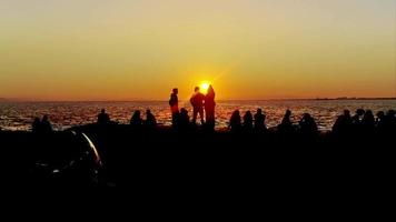 Silhouettes of People Sitting Against the Sun on the Beach at Sunset video