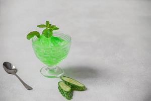 Summer cocktail frozen juice of fresh cucumber and mint on a white minimalist background, copy space. Summer coolness, a tonic cocktail of crushed ice, a kind of sherbet. photo