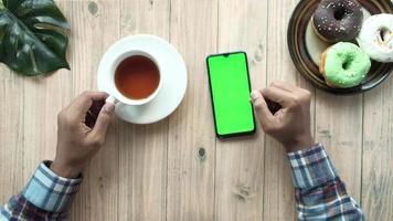 top view of man hand using smart phone and drinking tea on table video