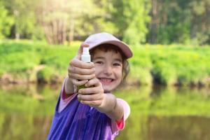 Girl sprays mosquito spray on the skin in nature that bite her hands and feet. Protection from insect bites, repellent safe for children. Outdoor recreation, against allergies. Summer time photo