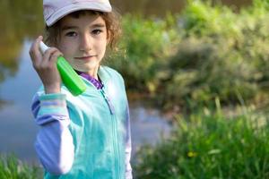 Girl sprays mosquito spray on the skin in nature that bite her hands and feet. Protection from insect bites, repellent safe for children. Outdoor recreation, against allergies. Summer time photo