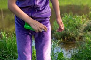 Girl sprays mosquito spray on the skin in nature that bite her hands and feet. Protection from insect bites, repellent safe for children. Outdoor recreation, against allergies. Summer time photo