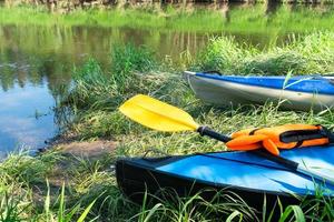 canoas turísticas con remos se encuentran en la costa del río en verano en una caminata acuática. rafting en kayaks dobles y triples hinchables y con armazón, viaje en familia, aventura extrema en verano foto