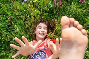 Portrait of a child girl in summer lying in the grass and wildflowers with heels and palms. summer time, freedom photo