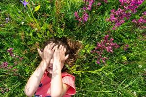 retrato de un niño niña en verano acostado en el césped y flores silvestres con tacones y palmas verano tiempo, libertad foto