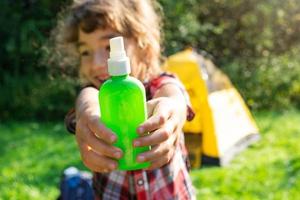 Girl sprays mosquito spray on the skin in nature that bite her hands and feet. Protection from insect bites, repellent safe for children. Outdoor recreation, against allergies. Summer time photo