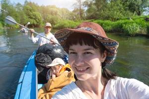 Man and woman couple, baby is sleeping, selfies are happy in family kayak trip rowing boat on the river, water hike, a summer adventure. Eco-friendly and extreme tourism, active and healthy lifestyle photo