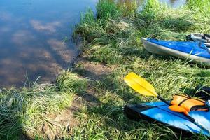 canoas turísticas con remos se encuentran en la costa del río en verano en una caminata acuática. rafting en kayaks dobles y triples hinchables y con armazón, viaje en familia, aventura extrema en verano foto