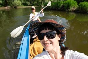 Man and woman couple, baby is sleeping, selfies are happy in family kayak trip rowing boat on the river, water hike, a summer adventure. Eco-friendly and extreme tourism, active and healthy lifestyle photo