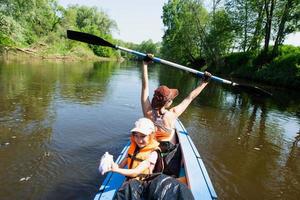 familia kayac viaje. mamá y hija remo un barco en el río, un agua caminata, un verano aventura. Respetuoso del medio ambiente y extremo turismo, activo y sano estilo de vida foto
