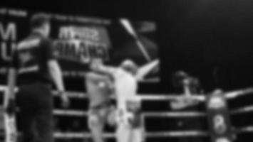 Blurred images black and white photo style of Thai boxing or Muay Thai or Kickboxing which local and foriegn boxer are fighting on the ring at indoor stage as martial art sport. Muay Thai Kick boxing