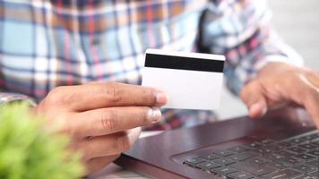 homem com as mãos segurando um cartão de crédito e usando laptop para fazer compras online video