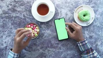 Mens hand- gebruik makend van slim telefoon en aan het eten popcorn video