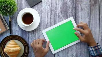 arrière vue de Jeune homme poursuivre numérique tablette avec vert écran video