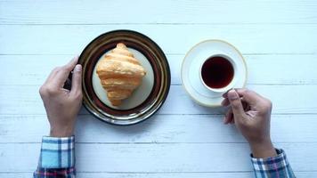 fresh baked croissant on plate and cup of tea on table video