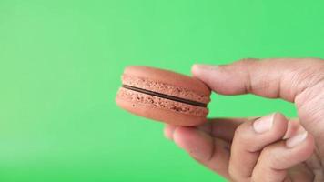 woman holding chocolate color macaroon close up video