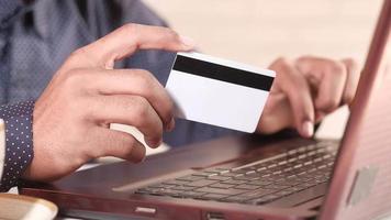 mains d'homme tenant une carte de crédit et utilisant un ordinateur portable pour acheter en ligne video