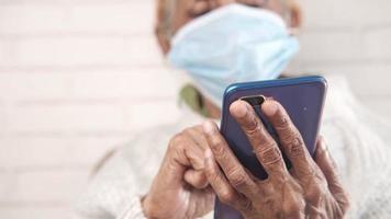 sick senior woman with face mask hand using smart phone close up video