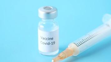 Close up of coronavirus vaccine and syringe on blue background video