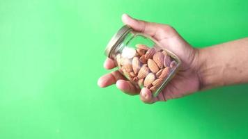 hand holding a jar of almond nuts against green background video
