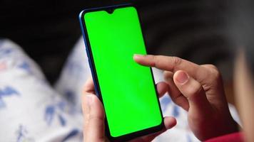 young man hand holding smart phone with green screen video