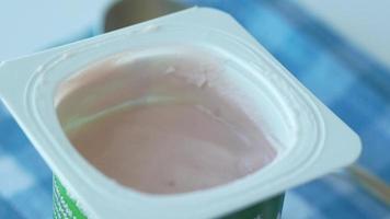 fresh yogurt in a plastic container and spoon on table . video
