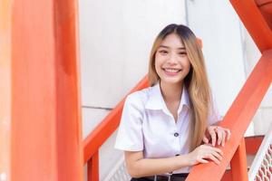 Portrait of young Thai student in university student uniform. Asian cute girl standing smiling happily and where her teeth are wearing retainers looking at the camera to present something confidently. photo