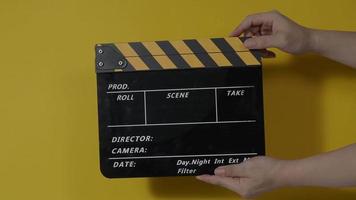 Film slate or Movie clapperboard hitting in front of cinema camera recording. Close up hand holding empty film slate and clapping it. Open and close film slate for video production. film production.