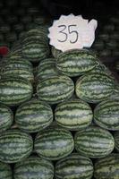 The neatly arranged pile of watermelons with one fruit cut open revealing its red flesh. These watermelons are being sold at a fruit market in Thailand photo