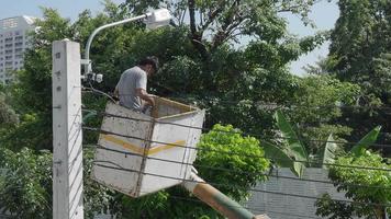 Worker on height lifting platform installing new street light bulb. Electrician work service mounting street light. Replacement of old  lamps with new LED lighting. Technician light repair light pole video