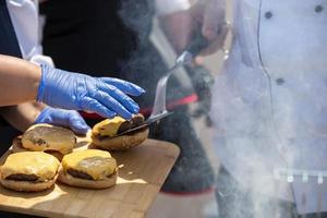 The hands of the cook make a hamburger. Fast food preparation process. photo