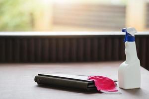 A bottle of cleanser and a medical mask on a restaurant table. photo