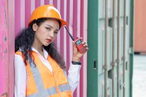 Portrait of female worker In Cargo Containers In Shipping Container Yard. woman holding walkie-talkie and digital tablet. photo