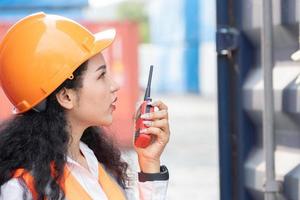 Portrait of female worker In Cargo Containers In Shipping Container Yard. woman holding walkie-talkie and digital tablet. photo