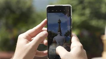 fechar acima do turista levando uma foto com uma telefone do Swayambhunath stupa dentro Katmandu, Nepal. macaco têmpora. video