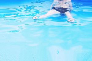 boy swims in the pool. boy learning to swim.  feet in the pool close photo