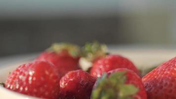 Close up of hand picking up a strawberry from a bow video