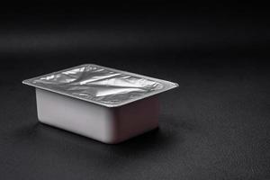 Rectangular plastic box with yogurt or cheese hermetically sealed with a foil lid photo