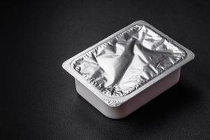 Rectangular plastic box with yogurt or cheese hermetically sealed with a foil lid photo