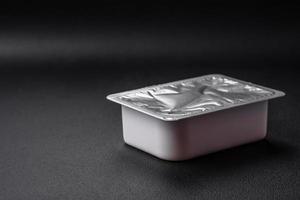 Rectangular plastic box with yogurt or cheese hermetically sealed with a foil lid photo