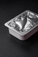 Rectangular plastic box with yogurt or cheese hermetically sealed with a foil lid photo