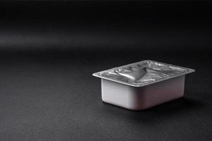 Rectangular plastic box with yogurt or cheese hermetically sealed with a foil lid photo