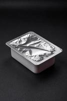 Rectangular plastic box with yogurt or cheese hermetically sealed with a foil lid photo