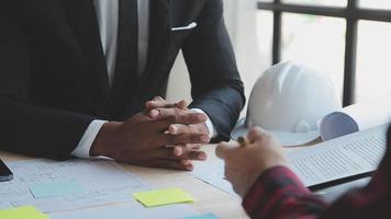 costruzione e struttura concetto di ingegnere o architetto incontro per progetto Lavorando con compagno e ingegneria utensili su modello edificio e planimetria nel Lavorando luogo, contrarre per tutti e due aziende. video